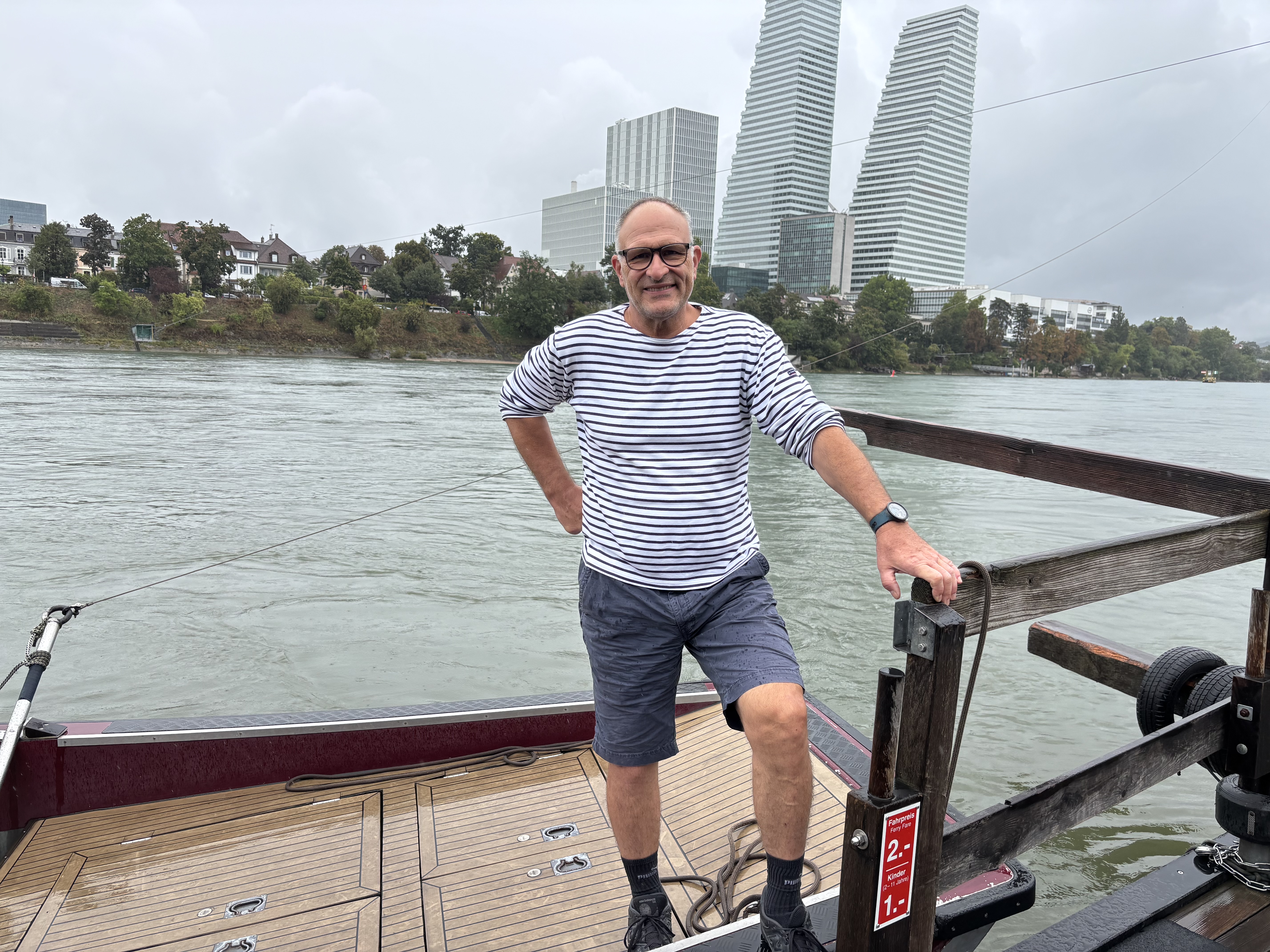 Philipp Schenker am Steg auf der Fähre. Im Hintergrund die Roche-Türme.